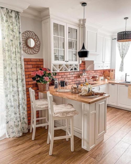 Легкий и воздушный интерьер с уютной кухней с фартуком из красного кирпича и белой спальней с деревянными деталями. 08