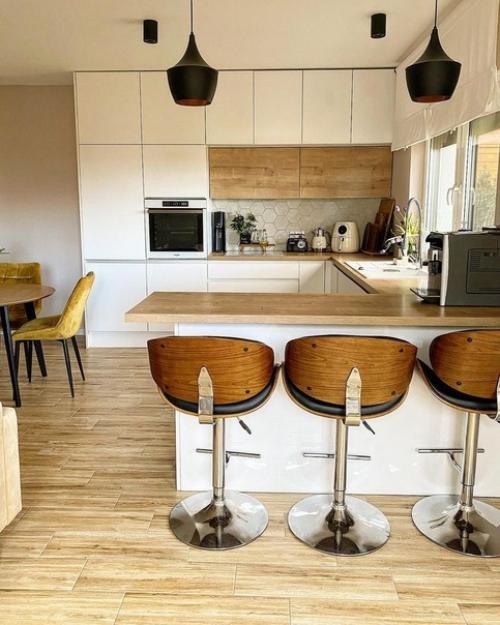 Кухня с белыми и деревянными фасадами, деревянными барными стульями на металлических ножках и круглым столом выглядит очень стильно. 01